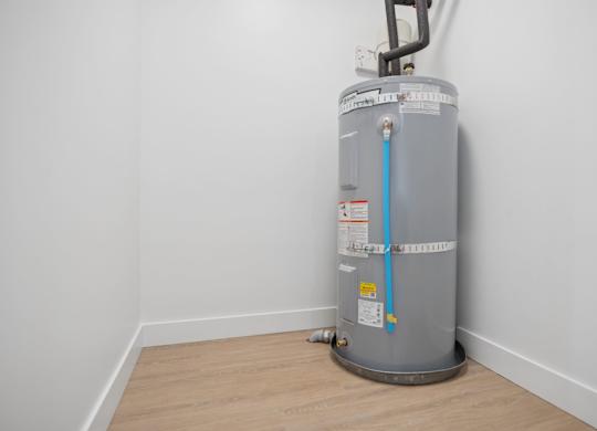 A water heater is installed in a room with white walls.