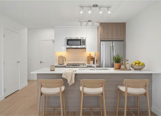 A modern kitchen with a white countertop and wooden bar stools.