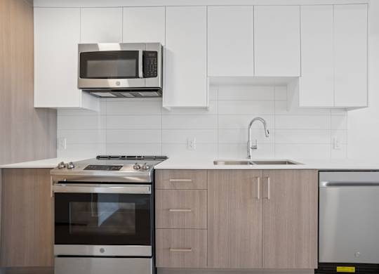 A modern kitchen with a stainless steel oven and microwave above a sink.