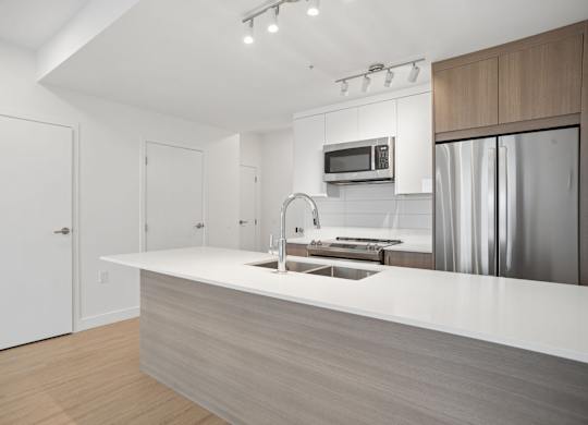 A modern kitchen with a white countertop and stainless steel appliances.