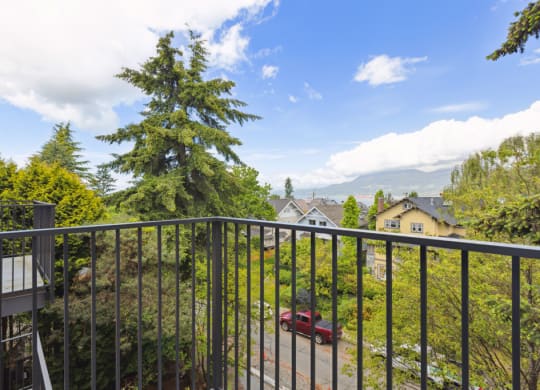 the view from the balcony of a home with a red car in the yard