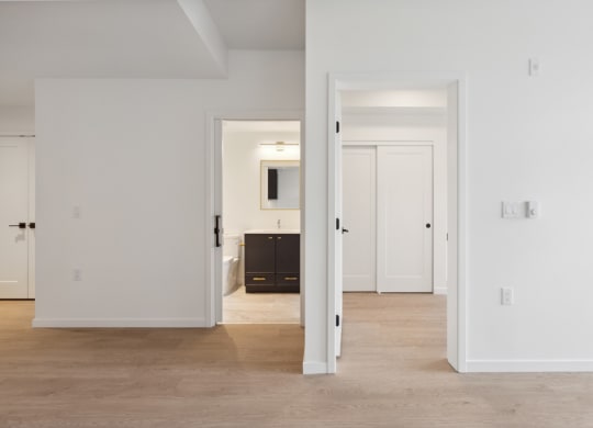 an open doorway into a living room and a hallway to a bedroom and a bathroom