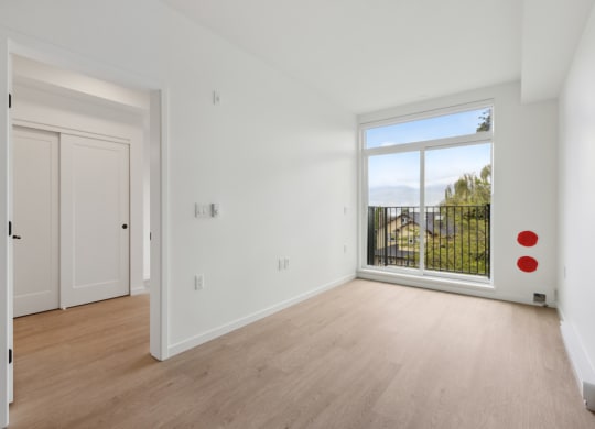 an empty living room with a large window and wooden floors