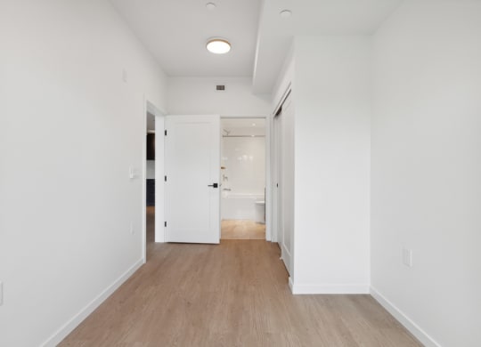 an empty hallway with white walls and wood floors