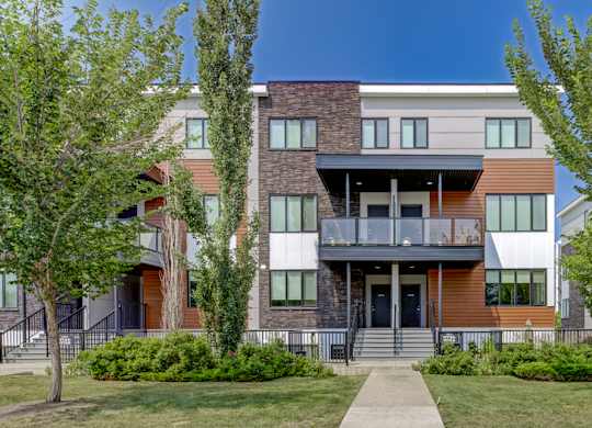 A modern multi-story apartment building with a balcony on the second floor.