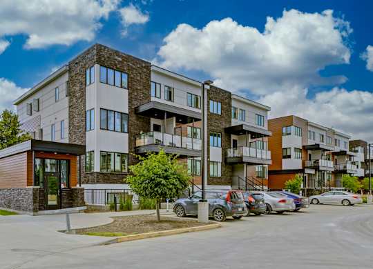 A modern apartment complex with a parking lot in front.