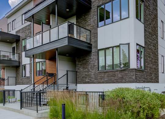 A modern two-story building with balconies and a mix of brick and siding exterior.