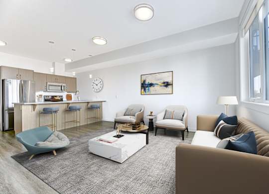 A modern living room with a kitchen area in the background.