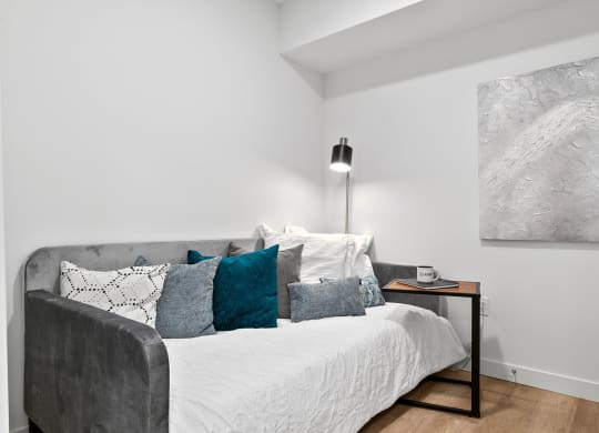 a bedroom with a bed and a nightstand with a clock and a painting on the wall