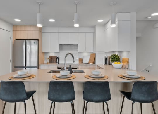 a kitchen with white cabinets and a large island with a sink and four chairs