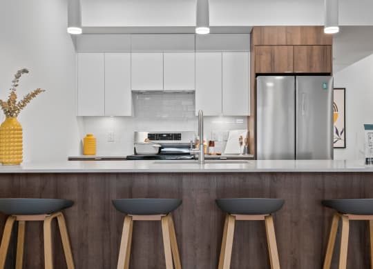 a kitchen with white cabinets and a large island with three stools in front of it