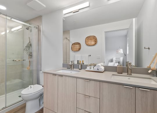 a bathroom with a toilet sink mirror and shower in a 555 waverly unit