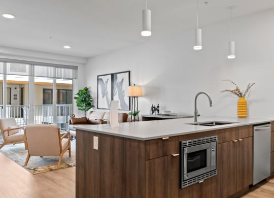 a kitchen with an island in front of a living room with a couch and chairs