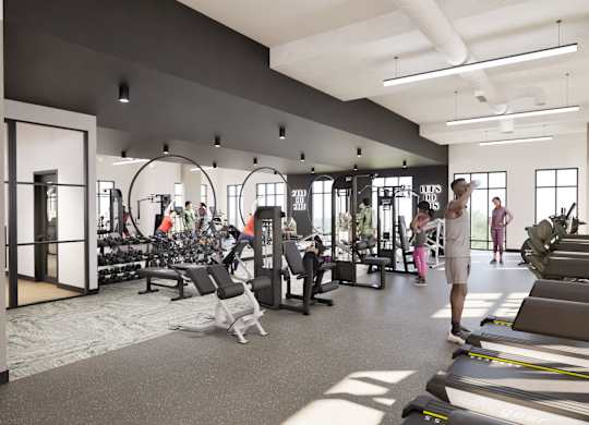 A man is walking through a gym with treadmills and other exercise equipment.