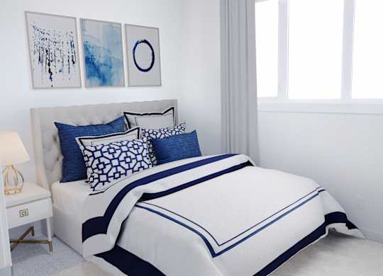 A bed with a white and blue comforter and pillows in a room with white walls.