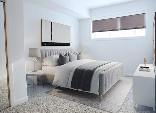 A bedroom with a large bed and a small table with a lamp on it.