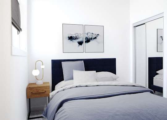 A bedroom with a bed, nightstand, and a painting on the wall.