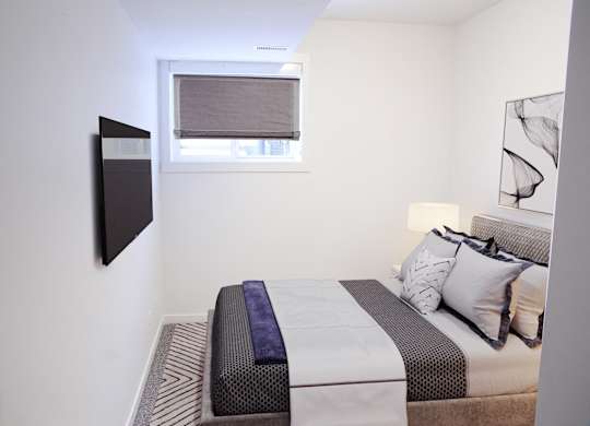 A bedroom with a bed, pillows, and a window.