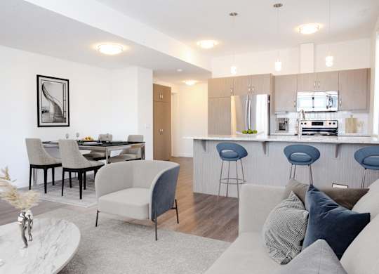 A modern living room with a kitchen in the background.