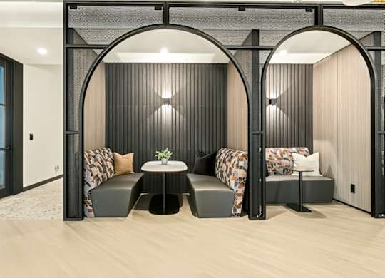 A modern room with a table and two chairs under a black arch.