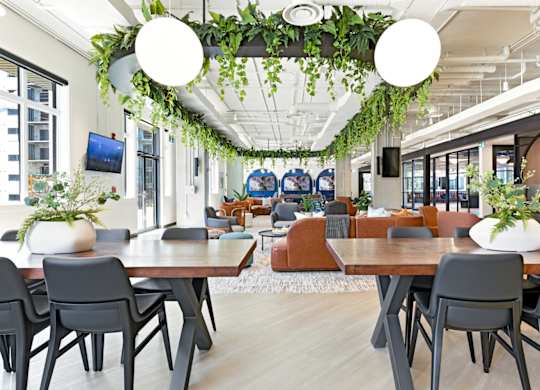 A modern dining area with wooden tables and grey chairs.