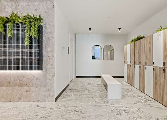 A long hallway with a bench and a wall of plants.