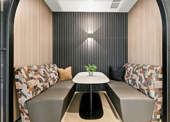 A small round table with a plant on it sits between two couches in a room with a striped wall.