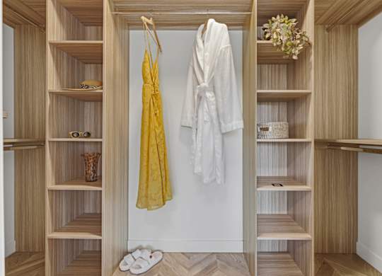 A white robe is hanging on a wooden closet door.