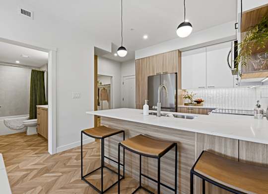 A kitchen with a white counter top and bar stools.