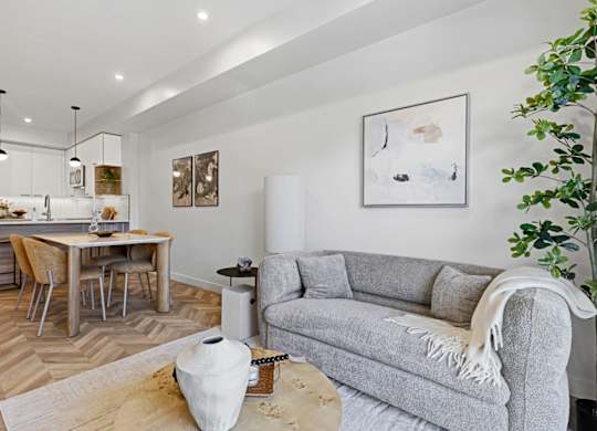 A modern living room with a grey couch and a wooden dining table.