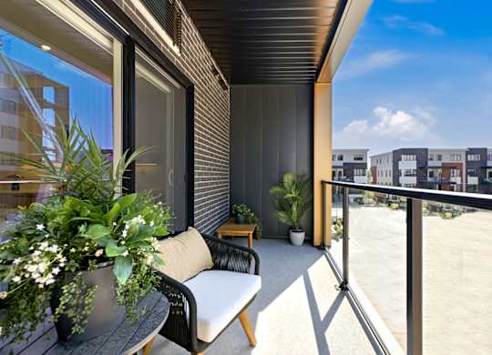A balcony with a chair and a table with a potted plant on it.