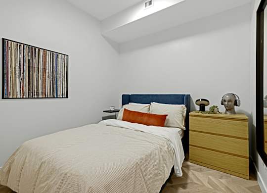 A bedroom with a bed, nightstand, and a picture on the wall.