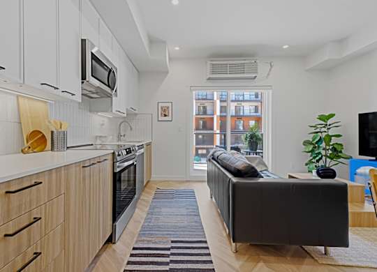 A modern kitchen with wooden cabinets and a black sofa.