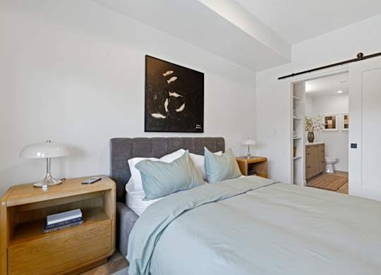 A bedroom with a bed, nightstand, and lamp.