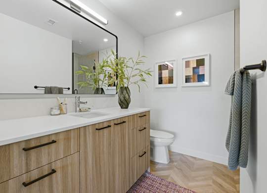 A bathroom with a white counter top and wooden cabinets.
