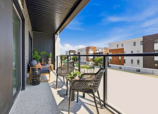 A balcony with a table and chairs overlooking a building.