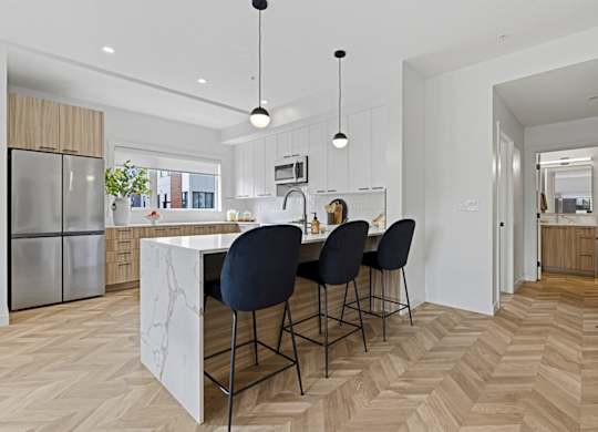 A kitchen with a marble island and four chairs.