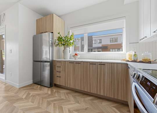 A kitchen with wooden cabinets and a stainless steel refrigerator.