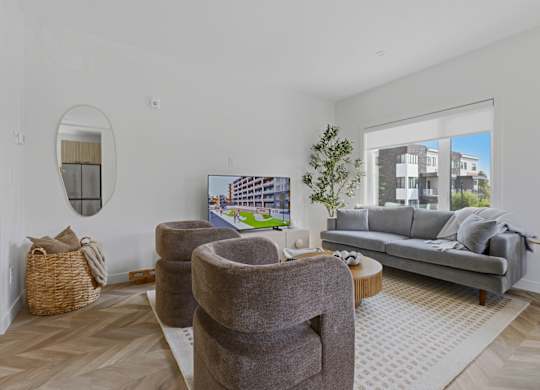 A living room with a grey couch, a round mirror, and a coffee table.