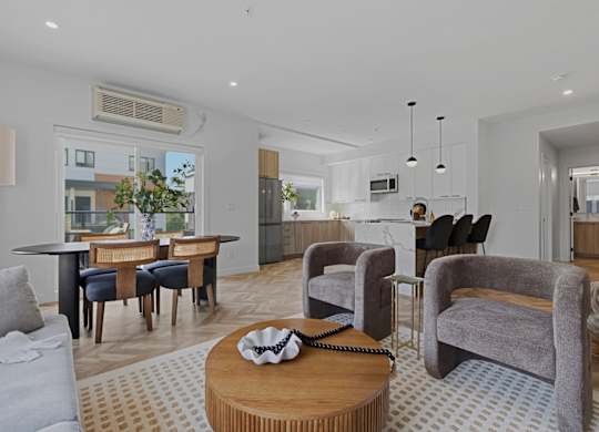 A living room with a grey couch, a wooden coffee table, and a large window.