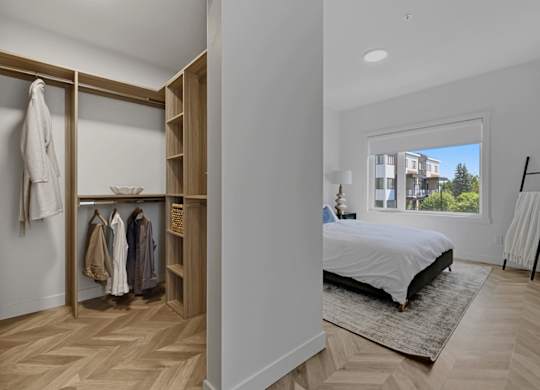 A bedroom with a large bed and a wardrobe with clothes hanging on it.