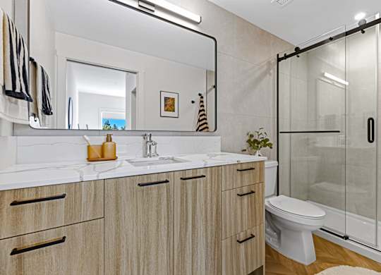 A bathroom with a white toilet, sink, and wooden cabinets.