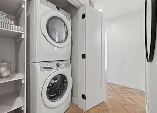 A white laundry room with a washer and dryer stacked on top of each other.