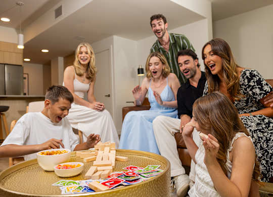 A group of people are gathered around a table playing a board game.