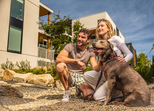A man and woman sitting on the ground with a dog.