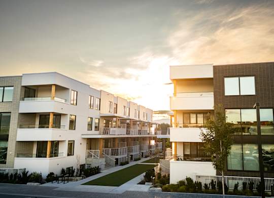 A modern apartment complex with a sunset in the background.