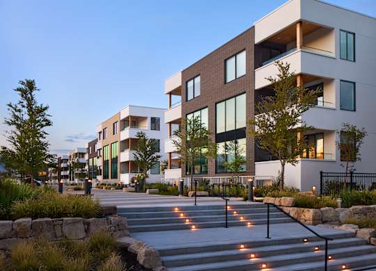 A modern building with a lot of windows and a stone wall in front.