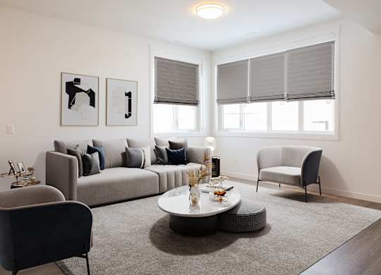 A living room with a grey couch, a grey armchair, a round coffee table, and two framed pictures on the wall.