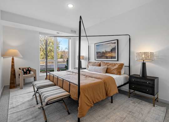 A bedroom with a large bed and a chair by the window.