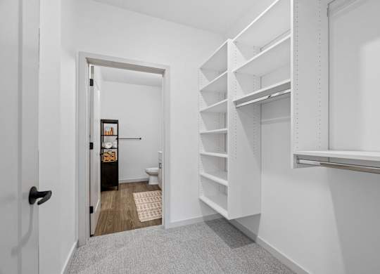 A white hallway with a doorway leading to a bathroom.